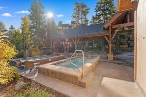 A pool area with multiple hot tubs and lounge chairs, surrounded by trees and a covered pavilion. - Breckenridge Mountain Retreat w/ Loft | Steps to Adventure (Breckenridge)