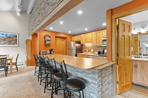 A modern kitchen with a central island, wooden cabinets, and a stone backsplash. - Breckenridge Mountain Retreat w/ Loft | Steps to Adventure (Breckenridge)