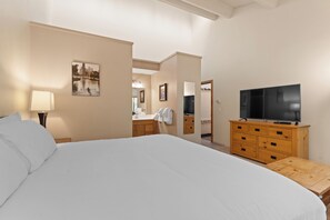 Ein Hotelzimmer mit einem großen Bett, einer Holzkommode, einem Fernseher und einem durch eine offene Tür einsehbaren Badezimmer.