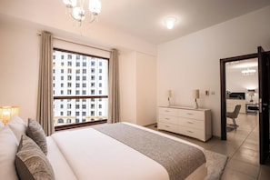 Une chambre d’hôtel avec un lit, une commode, un bureau et une vue sur un immeuble par la fenêtre.