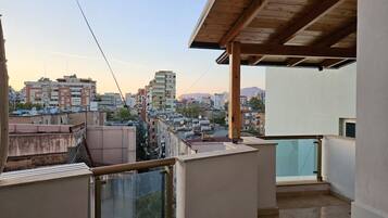 Un balcon offrant une vue sur le paysage urbain, avec des bâtiments et des montagnes visibles au loin.