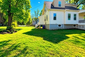 A two-story house with a front porch, a garage, and a well-maintained lawn. - Cape Cod Style 5-Bedroom Retreat with a wrap-around Porch in Vibrant Baltimore (Baltimore)