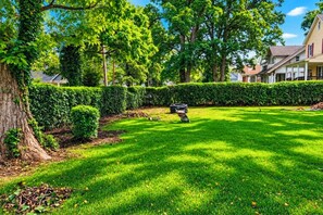 A well-maintained lawn with a stone sculpture, neatly trimmed hedges, and a large tree. - Cape Cod Style 5-Bedroom Retreat with a wrap-around Porch in Vibrant Baltimore (Baltimore)