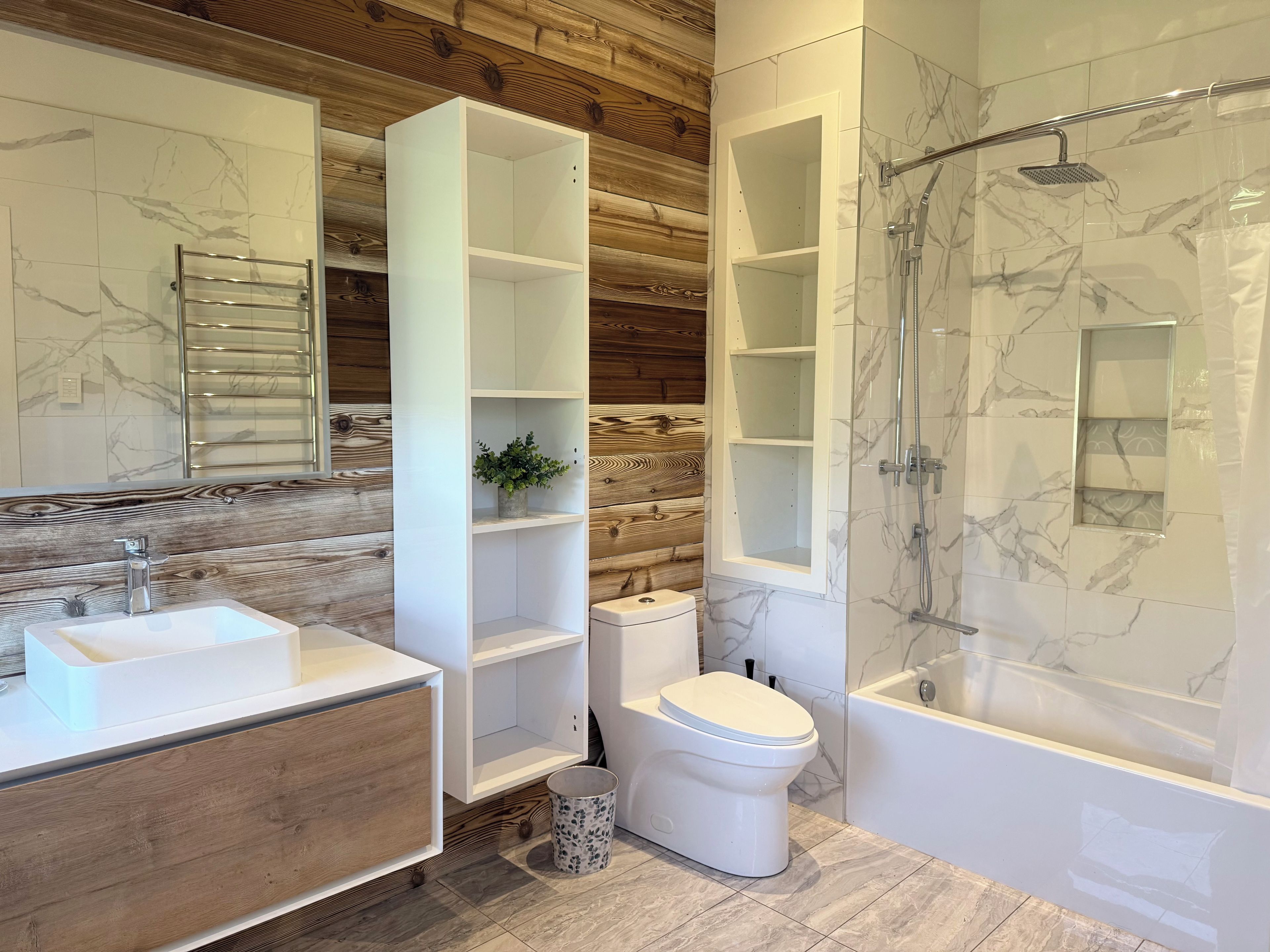 Un bagno moderno con pannello murale in legno, un lavandino bianco, un water e una zona doccia.