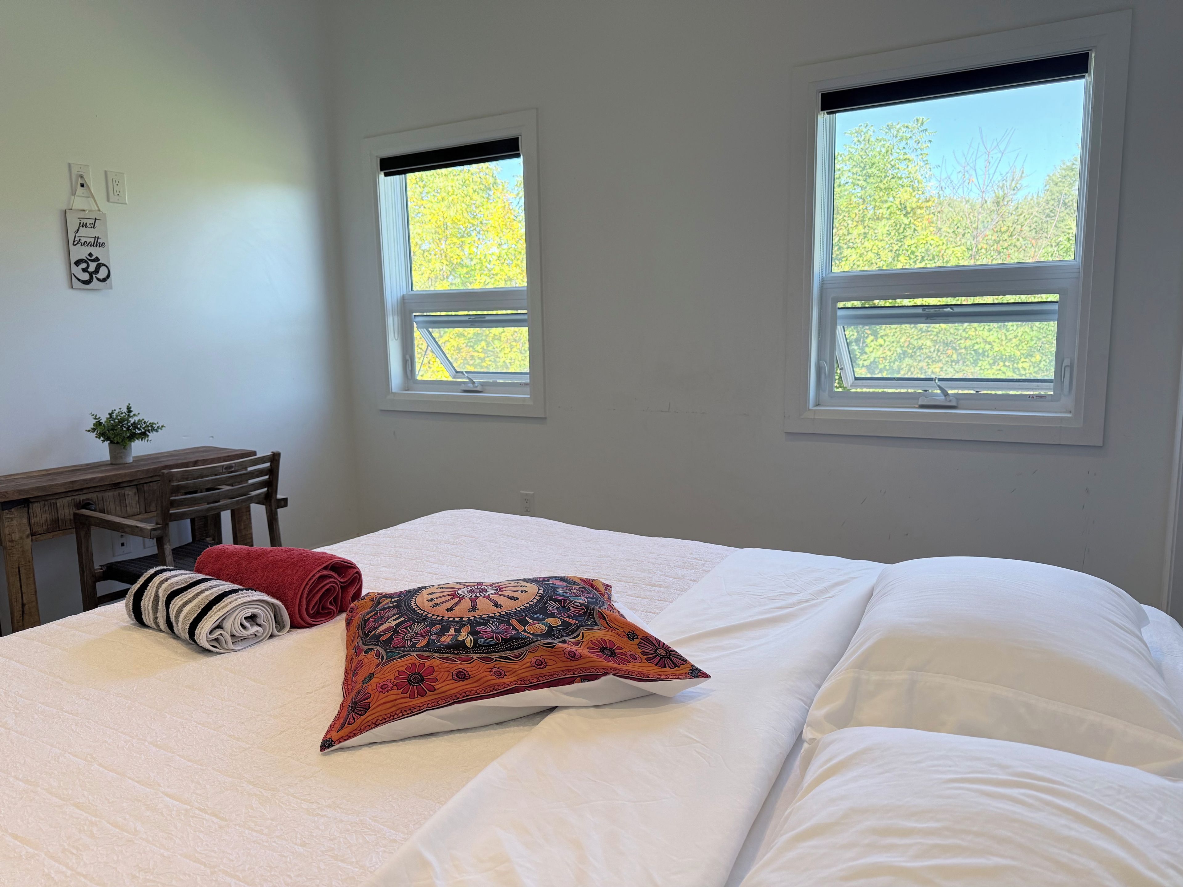 Una camera da letto con un letto, due finestre, una scrivania e un cartello appeso al muro.