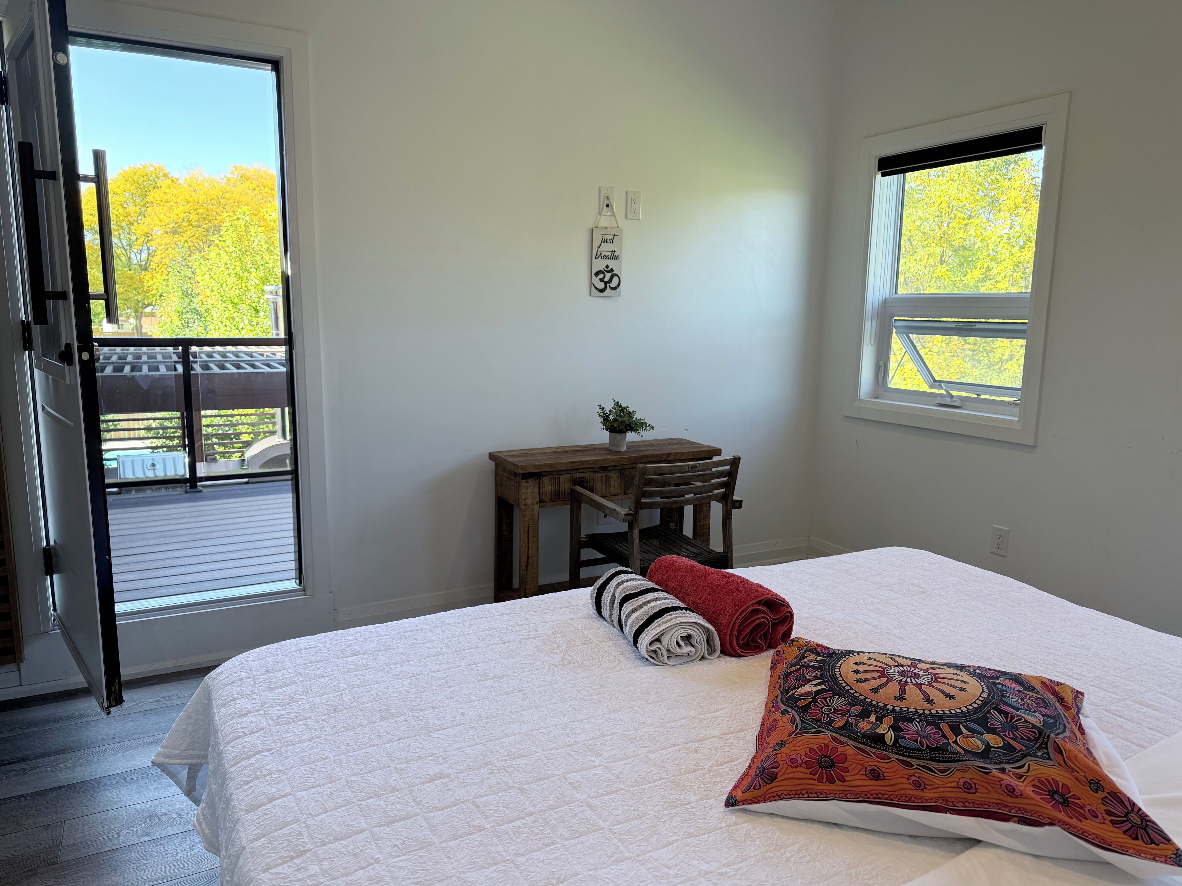 A bedroom with a bed, a window, a desk, and a chair.