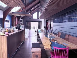Una cucina moderna con un'ampia penisola in legno, un'area pranzo con tavolo in vetro e vista sull'esterno.
