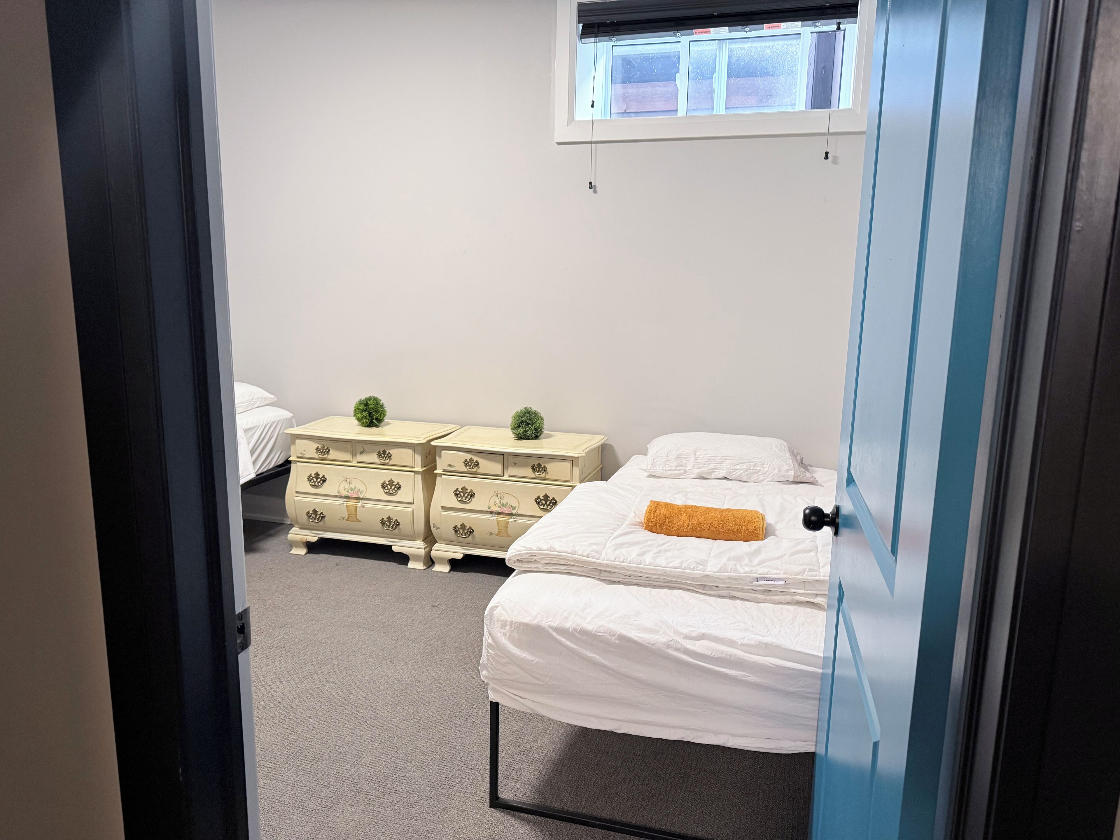 A bedroom with a bed, a dresser, and a window.