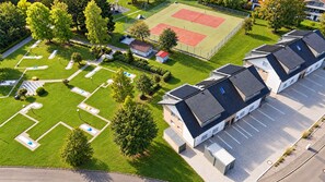 Een woongebied met een tennisbaan, een parkeerplaats en een gebouw met zonnepanelen.