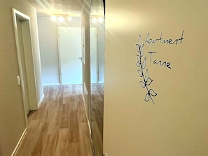 Ein Flur mit Holzboden und einer Wand mit Pflanze und Text.