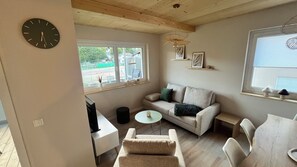 A cozy room with a sofa, a small table, a TV, and a clock on the wall. - Berg Apartment with a Balcony and a View of Nature in Herrischried – My SWH (Herrischried)