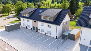 Ein modernes Gebäude mit flachem Dach, zahlreichen Fenstern und einem Parkplatz.