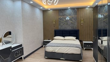 A modern bedroom with a large bed, bedside tables, a mirror, and a chandelier.