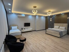 A modern bedroom with two beds, a TV, and a seating area.
