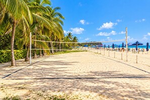 A beach volleyball court with a net, surrounded by palm trees and beach umbrellas. - Morros Park. Exclusive Beach & Nature Retreat (Bolívar)