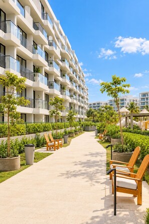 A modern multi-story hotel with a central walkway, outdoor seating, and greenery. - Morros Park. Exclusive Beach & Nature Retreat (Bolívar)