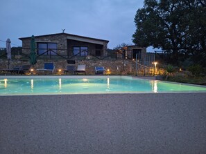 Ein Swimmingpool mit Liegestühlen und einem Steinhaus im Hintergrund.