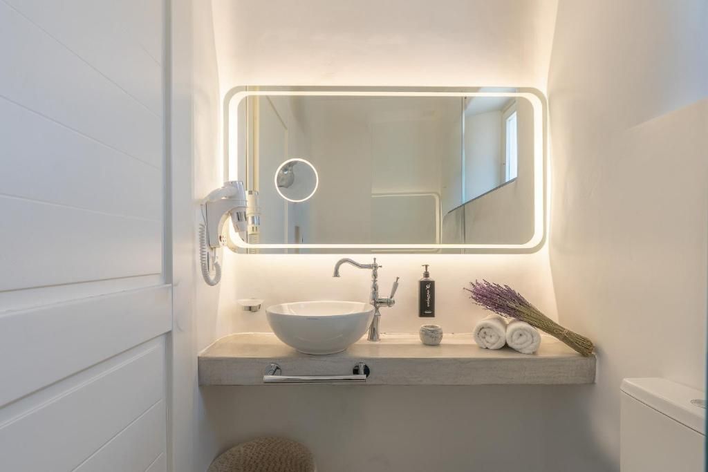 A bathroom with a white sink, a mirror with a light, and a towel rack.