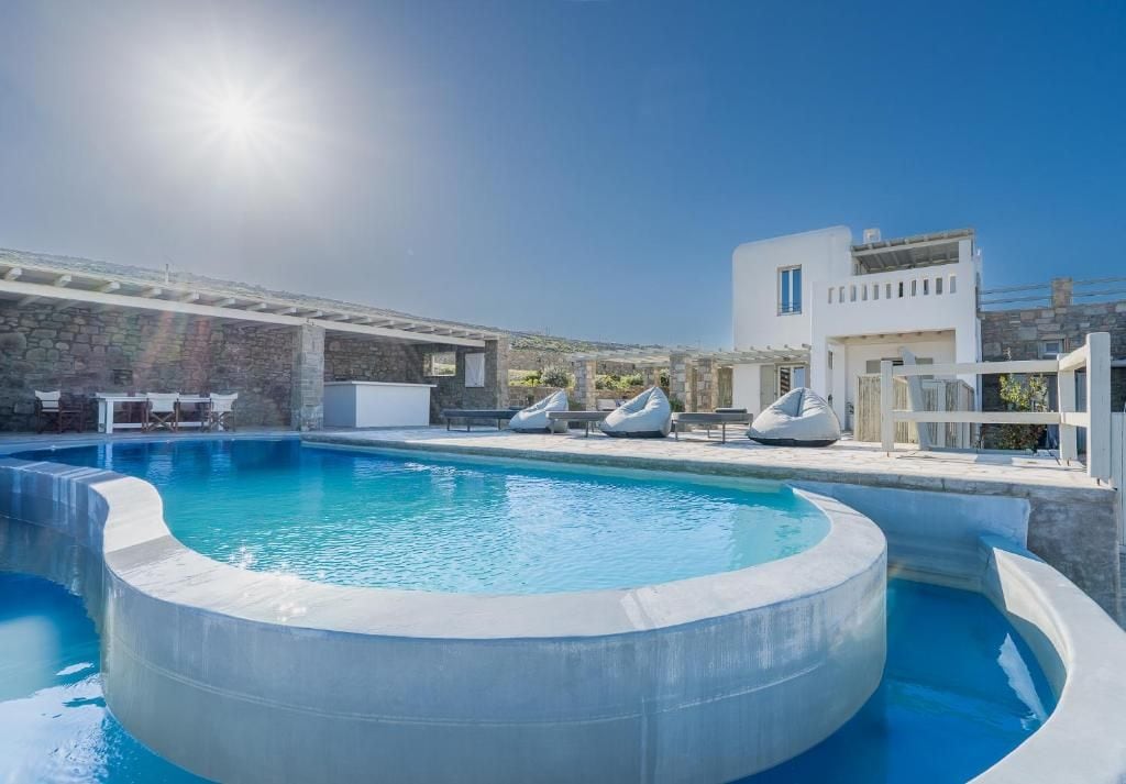 A pool area with a hot tub, lounge chairs, and a building with a white facade.