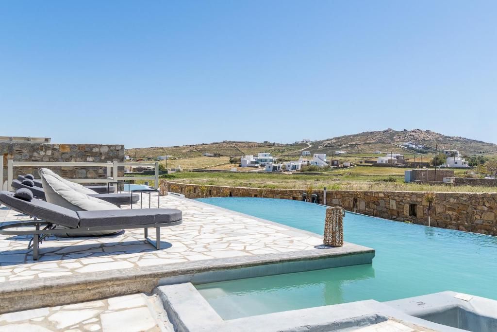A pool area with lounge chairs and a view of a hillside with buildings.