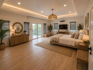 A spacious bedroom with a large bed, a TV, and a balcony. - Luxurious 6 bed, 7 bath estate in Fitches Creek for large families and groups (Fitches Creek)