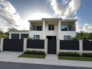 A modern two-story house with a flat roof, a front garage, and a gated entrance. - Luxurious 6 bed, 7 bath estate in Fitches Creek for large families and groups (Fitches Creek)