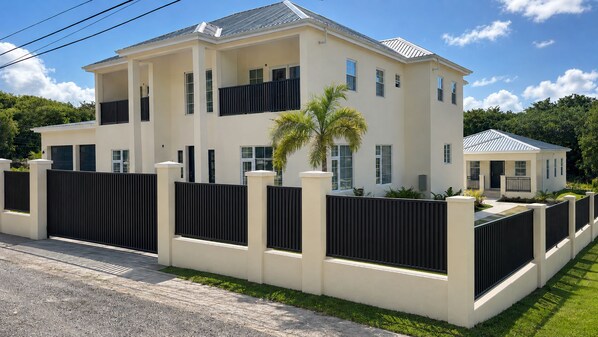 A two-story residential building with a symmetrical facade, a black fence, and a well-maintained lawn. - Luxurious 6 bed, 7 bath estate in Fitches Creek for large families and groups (Fitches Creek)