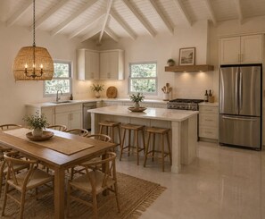 A modern kitchen with white cabinetry, a central island, stainless steel appliances, and a hanging light fixture. - Luxurious 6 bed, 7 bath estate in Fitches Creek for large families and groups (Fitches Creek)