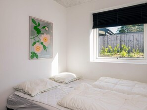 A bedroom with a single bed, a window with a view of a wooden fence and greenery, and a framed floral artwork on the wall. - 4 Star Holiday Home in Ebeltoft (Ebeltoft)