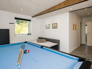 A pool table with cues and balls, a window with a view of greenery, and a sofa with cushions. - 4 Star Holiday Home in Ebeltoft (Ebeltoft)