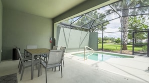 Ein Poolbereich mit Tisch und Stühlen, eine überdachte Sitzecke und Blick ins Freie.