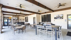 A spacious indoor dining area with multiple tables and chairs, ceiling fans, and a stone wall. - 4BR Townhome Solterra Resort Lazy River & Pool (Davenport)