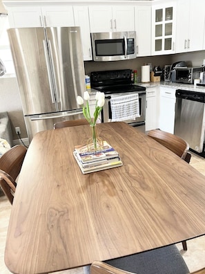 Eine moderne Küche mit Edelstahlgeräten, einem Holzespeisetisch und einer Vase mit weißen Blumen sowie einem Stapel Kochbücher.