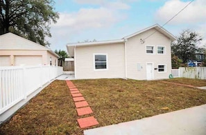 A single-story house with a front yard, a white picket fence, and a paved driveway. - Stylish 3-Bedroom, 2 Bath Home near Tampa Airport, Downtown & Raymond James Stadium (Tampa)