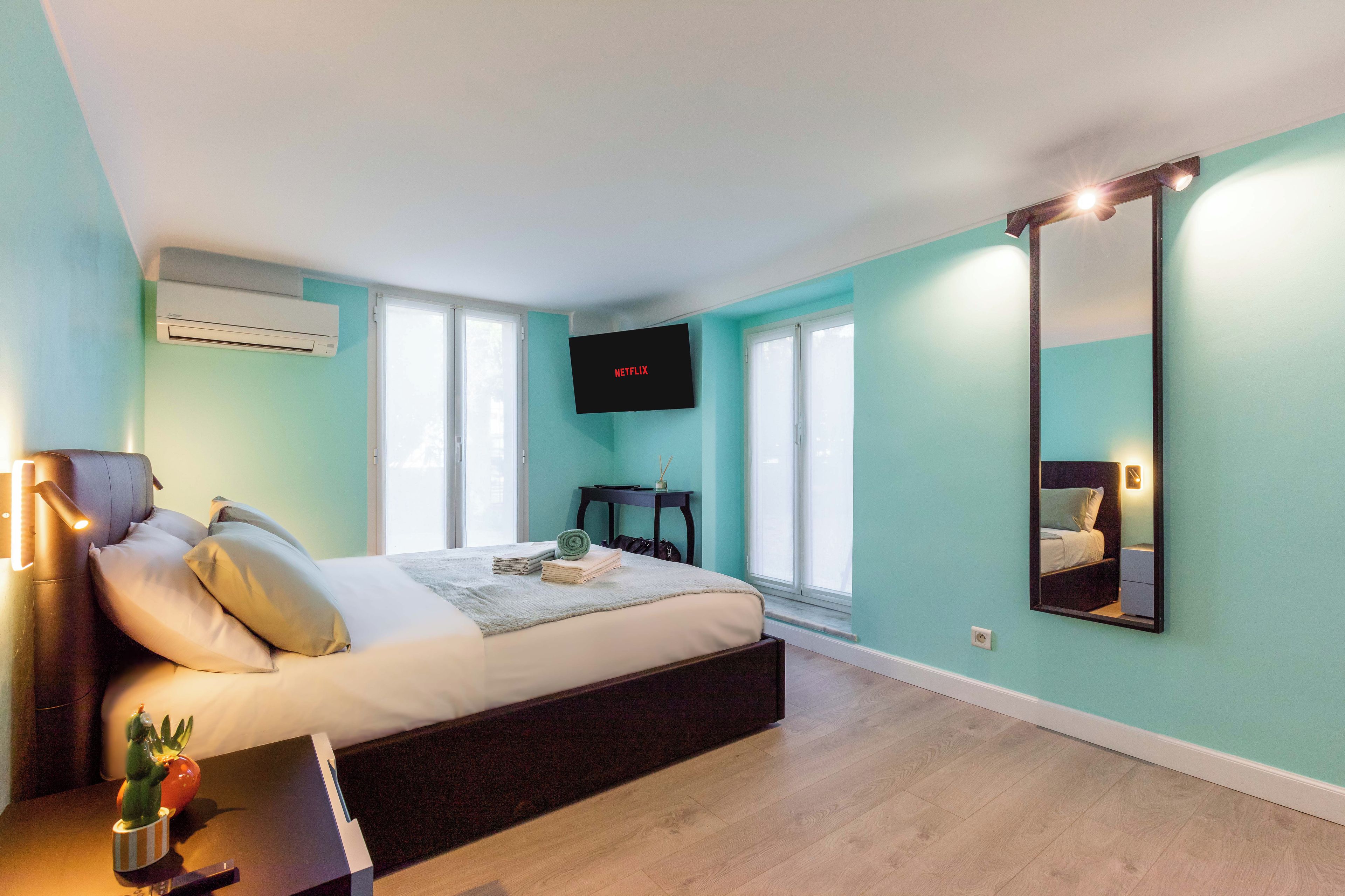 Quarto moderno com cama, televisão de tela plana, espelho e janela.