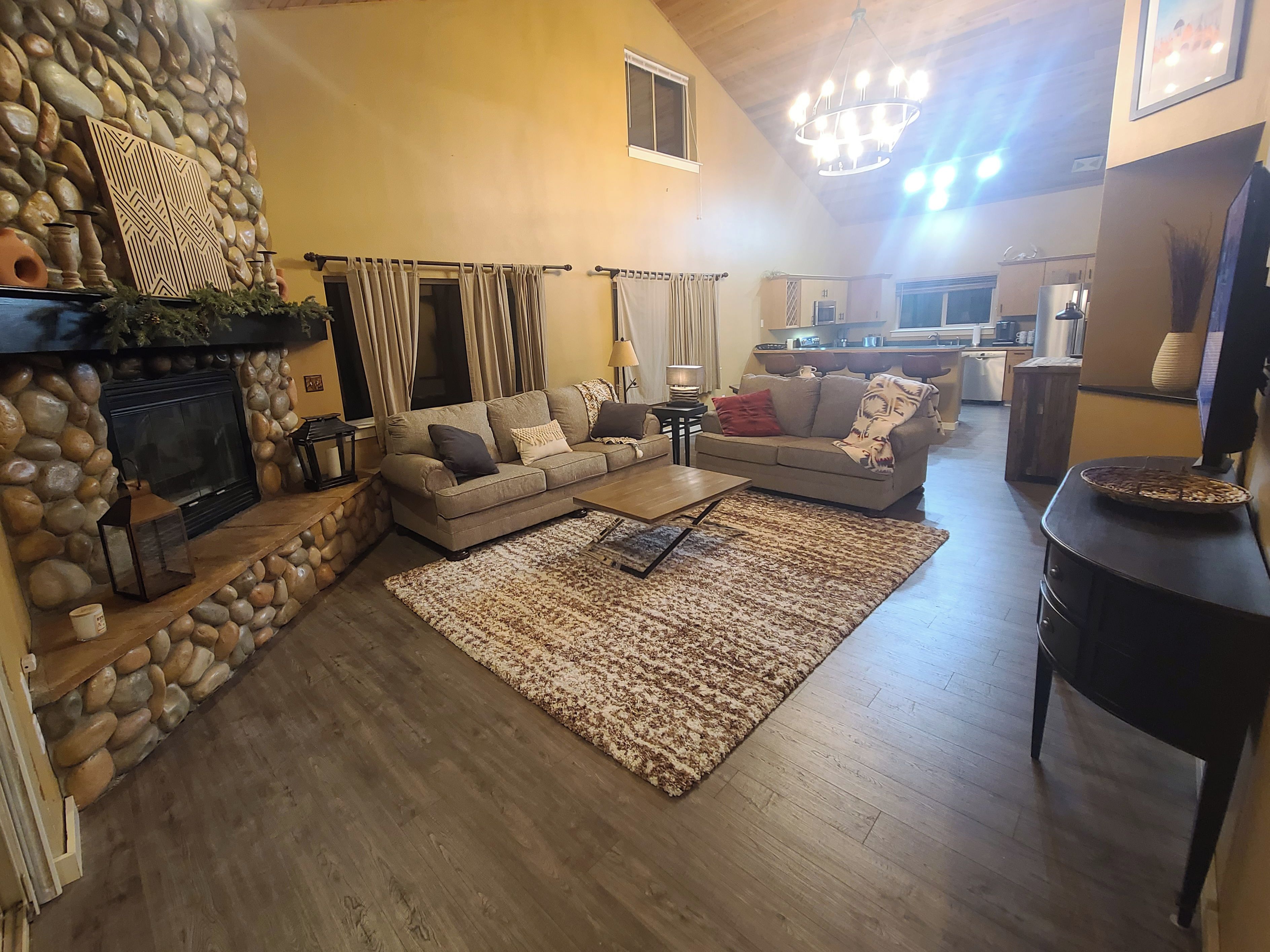 A living room with a stone fireplace, a sofa set, a coffee table, and a rug.