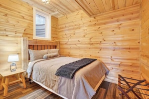 A wooden room with a bed, a nightstand, a window, and a wooden floor. - The Outpost, 5 minutes to Old Man's Cave, Sleeps 10, Hot Tub, Fire Pit. (Logan)