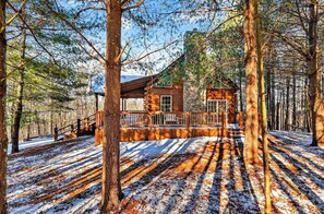 A cabin in a forest with a wooden deck and a covered area. - The Outpost, 5 minutes to Old Man's Cave, Sleeps 10, Hot Tub, Fire Pit. (Logan)