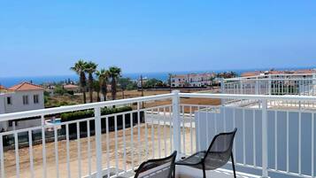Un balcon avec deux chaises et une vue sur la mer et les bâtiments.