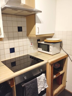 A compact kitchen with a built-in microwave, a stovetop, and a small oven. - Entire 1 bed, zone 2, Peckham, Camberwell, Elephant and Castle (London)