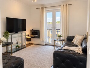 A modern living room with a flat-screen TV, a glass coffee table, a leather sofa, and a fireplace. - Entire 1 bed, zone 2, Peckham, Camberwell, Elephant and Castle (London)