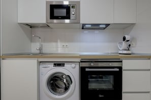 Eine kompakte Küche mit Mikrowelle, Backofen und Waschmaschine.