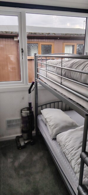 Dormitorio con literas, ventana, calentador y aspiradora.