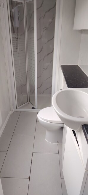 Un baño con inodoro, lavamanos y cabina de ducha.