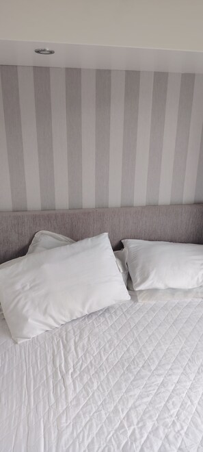 Ein Bett mit weißer Bettwäsche und einem gestreiften Kopfteil.