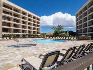A hotel pool area with lounge chairs, a hot tub, and a building with multiple balconies. - Sugar Beach PH08 | Penthouse Ocean Views, Beachfront Pool & Central A/C (Kihei)