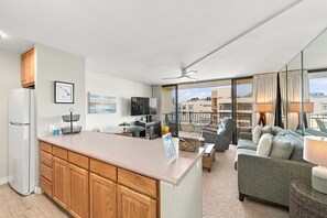A modern kitchen with wooden cabinets, a built-in refrigerator, and a dining area with a round table and chairs. - Sugar Beach PH08 | Penthouse Ocean Views, Beachfront Pool & Central A/C (Kihei)
