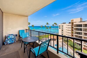 A balcony with a view of the ocean, a pool, and a building in the background. - Sugar Beach PH08 | Penthouse Ocean Views, Beachfront Pool & Central A/C (Kihei)
