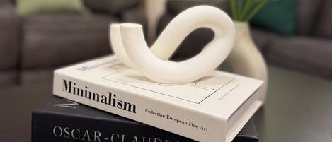 A book titled 'Minimalism' on a table with a vase of flowers and a lamp in the background.