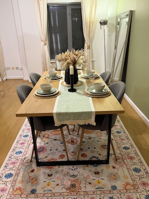 Une table à manger dressée avec des assiettes, des bols et un chandelier servant de centre de table, entourée de chaises.